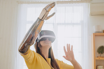 Positive young woman in casual clothes with modern bionic arm and virtual reality headset dances...