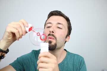 Cheerful guy plays with soap bubbles 