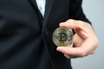Elegant businessman holding bitcoin between thumb and index finger
