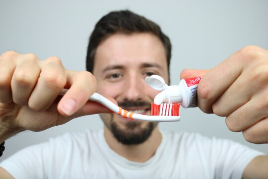 Caucasian man puts toothpaste on toothbrush