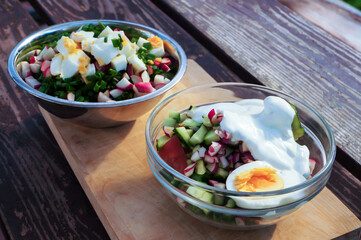 Fresh vegetables salad with eggs in bowls on wooden table.