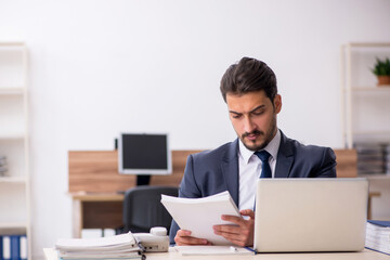 Young male employee sitting at workplace