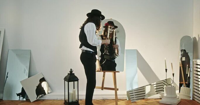 Dead not a calm soul of a dead man wandering with a candle in his hands looks terribly in the mirror dressed in a suit and hat