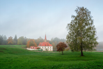 Fototapeta premium Autumn morning landscape. Bright autumn foggy landscape with golden trees and old Palace. Gatchina. Russia.