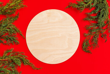 Blank empty round wood sign on red background with christmas tree branch, rustic wooden sign mockup