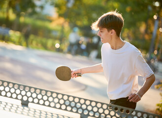 boy playing table tennis ping pong outdoors - obrazy, fototapety, plakaty