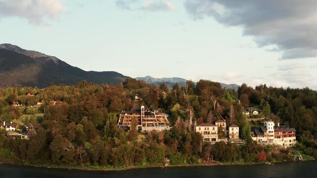 Aerial drone panning shot of luxury holiday homes and apartments on the shore of Lake Nahuel Huapi near Villa La Angostura in Patagonia, Argentina at sunset