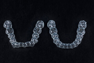 Transparent retainers brackets on black background with copy space. Dental orthodontic care
