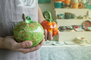Man holding DIY craft ceramic apple and pumpkins for halloween. Fall decoration in pottery workshop