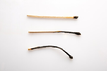 three Burnt wooden matches horizontally on white background.