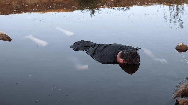 a man drowned , dead in the water , the body of a young man aged lying in the lake face down to the bottom, a corpse in a dirty pond unstable camera movement color correction.