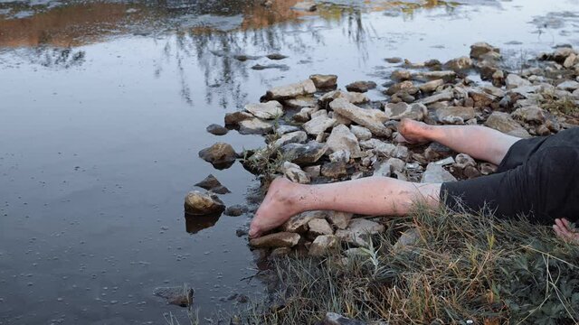 a murdered man , dead by the water , a body the corpse of a young man aged lying by the lake face down to the ground , a corpse by a dirty pond unstable camera movement color correction.