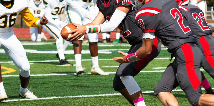 Football quarterback handing off the ball during a game
