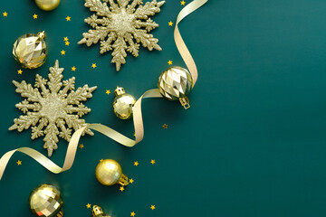 Elegant Christmas background with golden decorations, snowflakes, ribbon on green. Flat lay, top view.