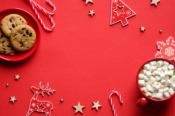 Tasty homemade Christmas cookies, hot cocoa with marshmallows, decorations on red background. Flat lay, top view, overhead.