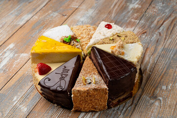 Sampling of different kinds of cake slices on wooden table, top view