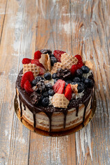 Drip cake with berries on wooden table, top view, catalogue shot