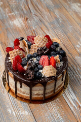 Drip cake with berries on wooden table, top view, catalogue shot