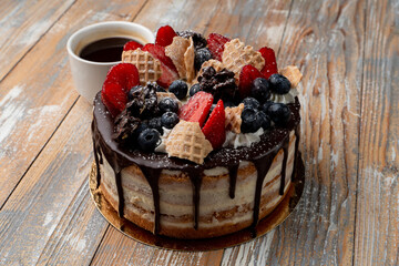 Trendy eastern european birthday cake with chocolate icing, strawberry and bluberry on a light wooden table, soft and natural colors, light photo