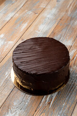 Very chocolate birthday cake with truffle ganache and perfect chocolate glazing on golden plate, top view, text space for commercial