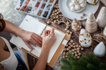 Top view of young woman is writing goals for New Year 2021 on diary on desk with Christmas Tree