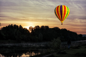 A bright hot air balloon on the background of bright orange sunset.