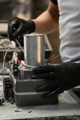closeup to the hands of a person repairing a metal object that is on his workplace, technology and equipment restoration in workshop, professional tools