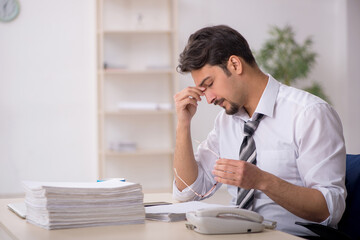 Young male employee unhappy with excessive work in the office