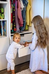 Teenage girl with long hair rolled up clothes use Marie Kondo's method. Placing apparel in cupboard