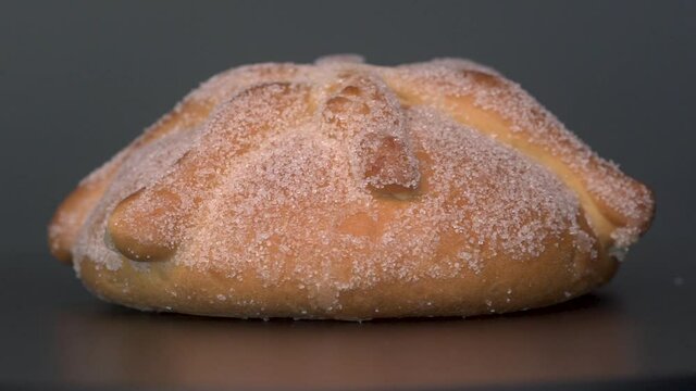 Traditional mexican bread of the dead or pan de muerto on grey background rotating video.  Bread baked to celebrate Day of the Dead.