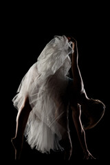ballerina with a white dress and black top posing on black background. side lit silhouette. © Nikola Spasenoski