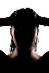 Silhouette portrait of a young brunette girl holding her hair with hands.