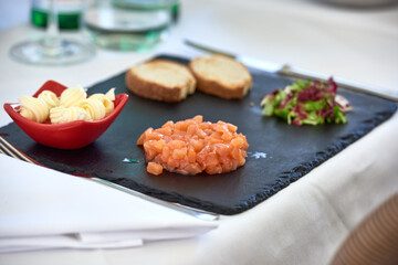 Fresh salmon tartar with toast and butter served on black plate