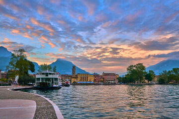 View of the beautiful Riva del Garda town at sunset with a red sky, Lake Garda surrounded by...