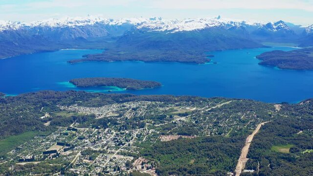 Aerial tilt shot of the town of Villa La Angostura in Argentina shot from Mount Cerro Bayo ski resort, looking out over lake Nahuel Huapi