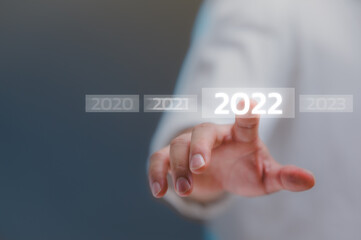 welcome year 2022. New year 2021 change to 2022 concept, businessman hand touching on 2022 virtual screen.