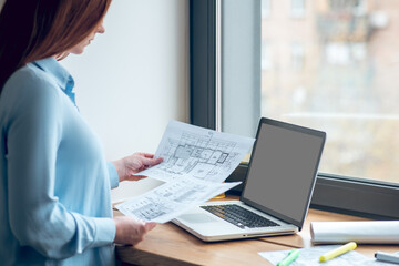 Focused woman reviewing construction plans on paper