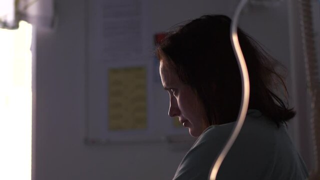 Sick apprehensive woman connected to IV intravenous drip. Dramatic tracking motion