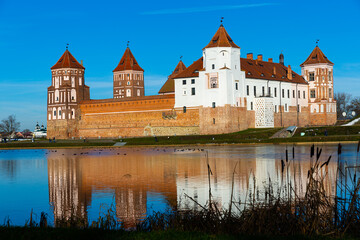 Fototapeta premium View of architectural ensemble of Mir Castle from pond in sunny winter day, Grodno region, Belarus