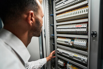 Data center worker reaching for electrical switch inside cabinet