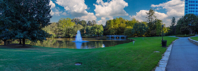 a stunning panoramic shot of a lake with a waterfall in the middle of the water surrounded by lush...