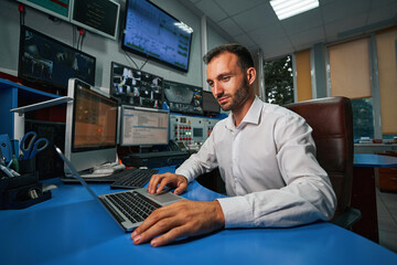 Male server administrator managing data center from control room