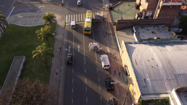 Aerial shot of bus and cars overtaking homeless poor person with bike transporting plastic and dirt  - Indigent Cartonero Misery poverty in Buenos Aires