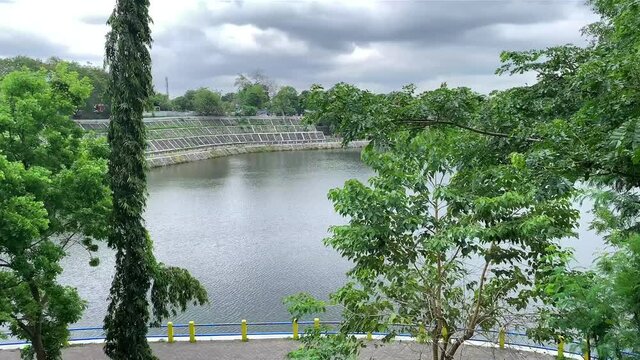 Aerial pan shot of local water reservoir with trees known with the name of embung tambak boyo