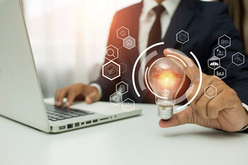 Business man holding light bulb on the Green background nature and writing on note book it for financial