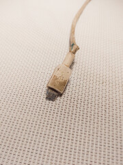 closeup of broken micro usb cable on white textured mat background, smartphone cable, charging cable, old cable with dirt and gunk