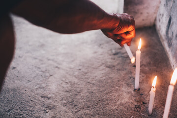 Hand lights a candle to pray in front of the tomb during a visit to a dead family member's  grave. Selective focus.