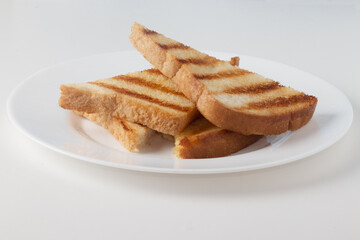 Toasted loaf bread with butter on white plate.
