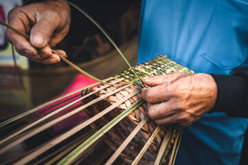 Hands weaving bamboo baskets at home