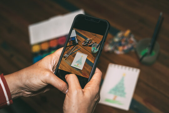 Taking a smartphone picture of a watercolor painting of a Christmas tree